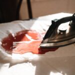 Come togliere le macchie di cera di candela dalla tovaglia usando il ferro da stiro e un foglio di carta