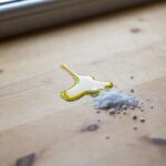 Il trucco del sale fino per assorbire l'olio rovesciato sul tavolo di legno in pochi secondi