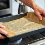 Il trucco della carta da forno bagnata e strizzata per foderare le teglie senza farla arricciare